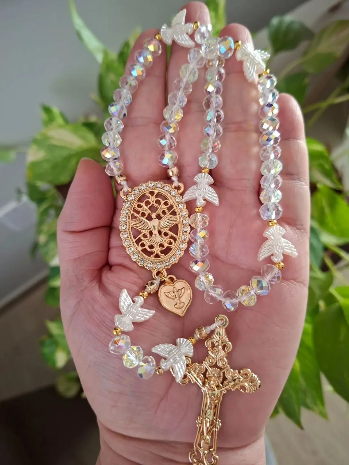 Terço de cristal boreal com pombas do Espírito Santo, segurado na mão